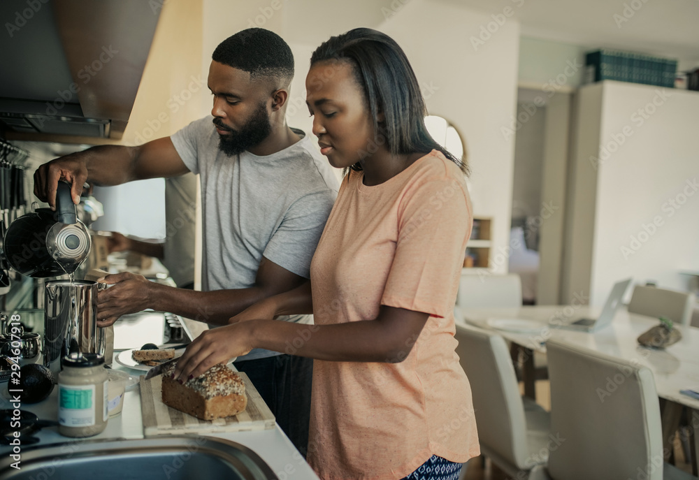 Smiling young African American couple preparing breakfast in their kitchen Smiling young African American couple preparing breakfast in their kitchen