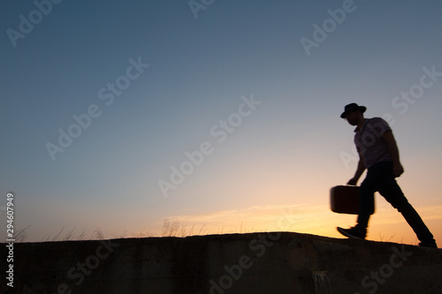 silhouette of man with suitcase at sunrise © robcartorres