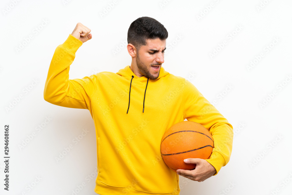 Handsome young basketball player man over isolated white wall celebrating a victory Handsome young basketball player man over isolated white wall celebrating a victory