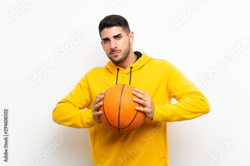 Handsome young basketball player man over isolated white wall
