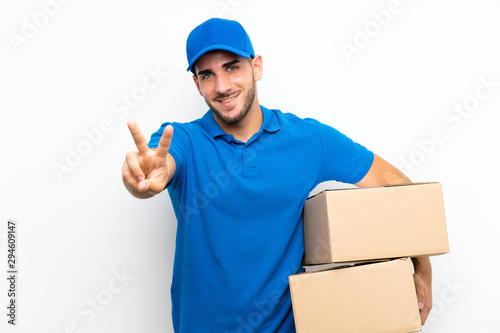 Delivery man over isolated white background smiling and showing victory sign