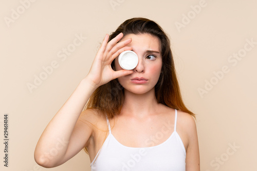 Young brunette girl with moisturizer over isolated background