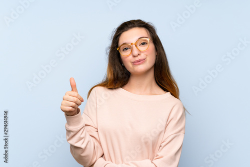 Young brunette girl over isolated blue background with glasses