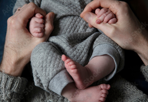Close up of a father holding new born babies hands