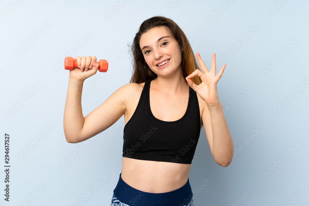 Young sport woman with weightlifting over isolated blue background showing ok sign with fingers Young sport woman with weightlifting over isolated blue background showing ok sign with fingers