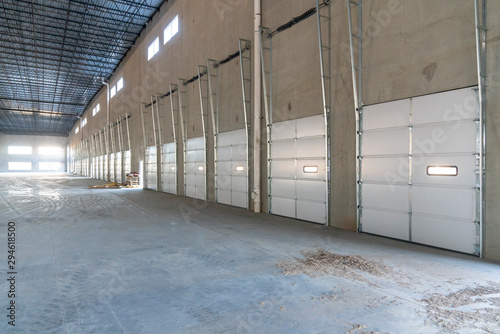 Overhead Garage Doors lining an empty warehouse.