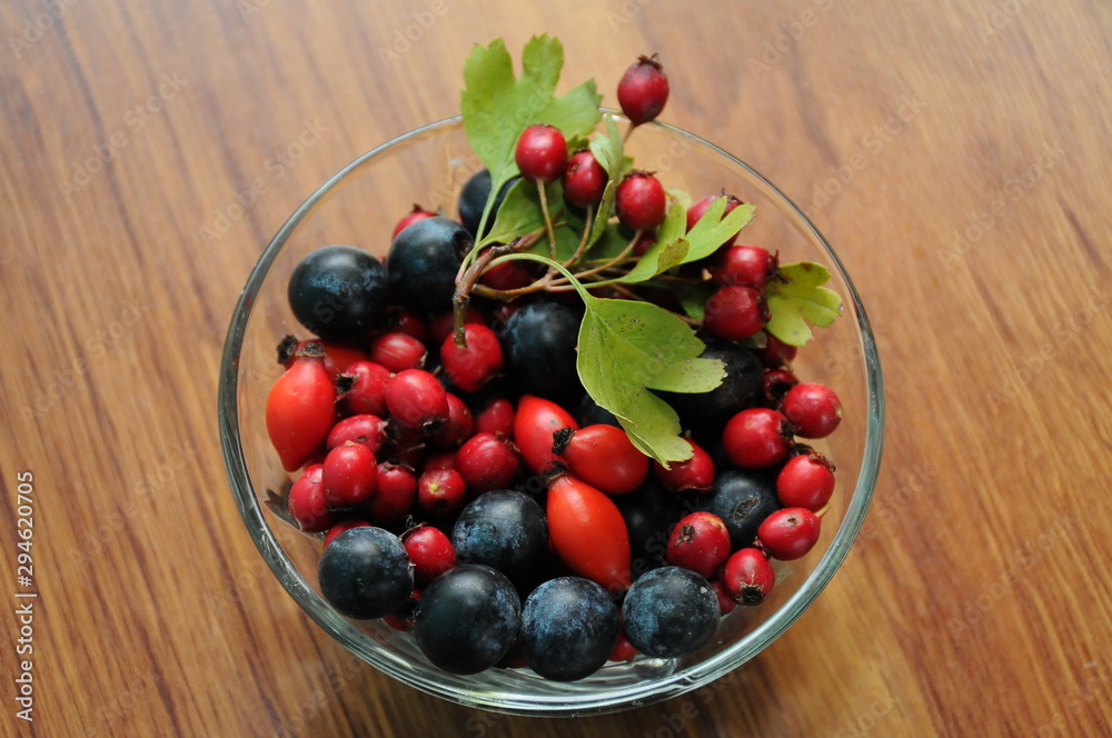 forest fruit in a glass bowl on a wooden table as decoration forest fruit in a glass bowl on a wooden table as decoration