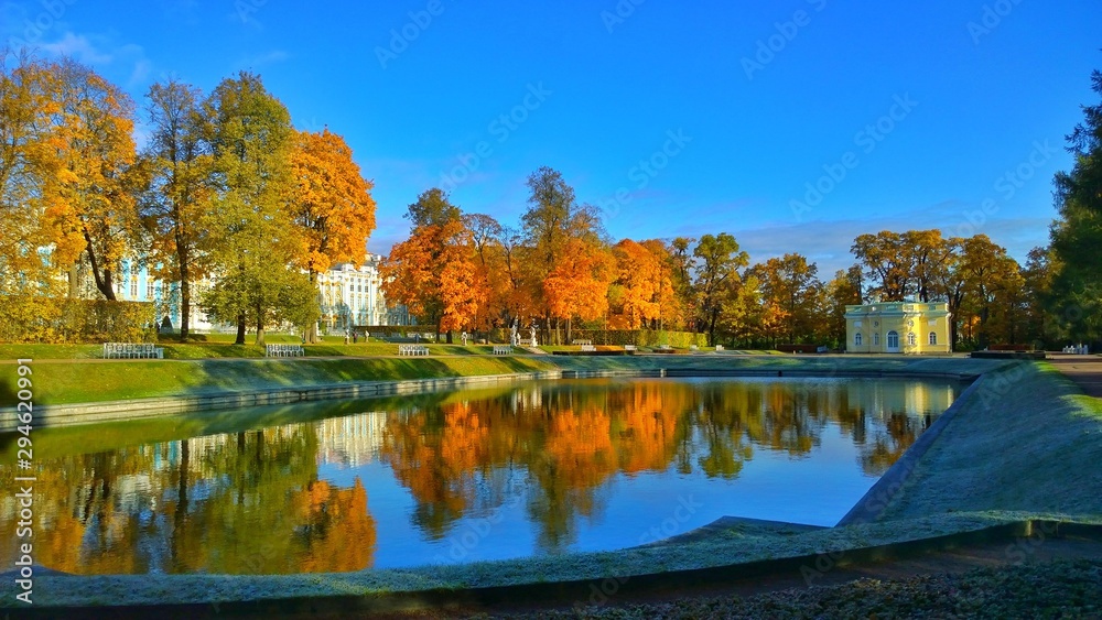 Golden Autumn in Catherine Park, city of Pushkin (Tsarskoye Selo), suburb of St. Petersburg, Russia. Pond and pavilion Upper Bathhouse. Reflection of orange trees and the Catherine Palace in the water