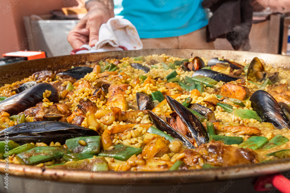 a large pan full of freshly prepared paella - cooking spanish sea food with rice, mussels and green beans