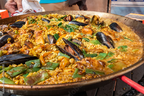 a large pan full of freshly prepared paella - cooking spanish sea food with rice, mussels and green beans