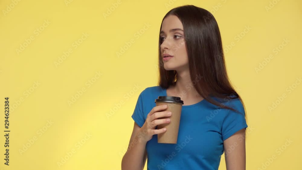 attractive woman holding paper cup and talking isolated on yellow attractive woman holding paper cup and talking isolated on yellow