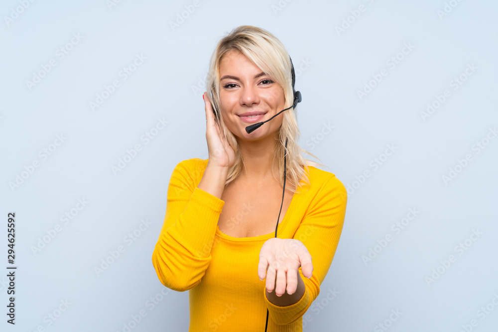 Naklejka premium Young blonde woman over isolated background working with headset