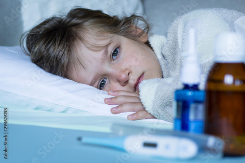 Exhausted, sick child with fever lying in bed. Healthcare and medical concept. Close up.