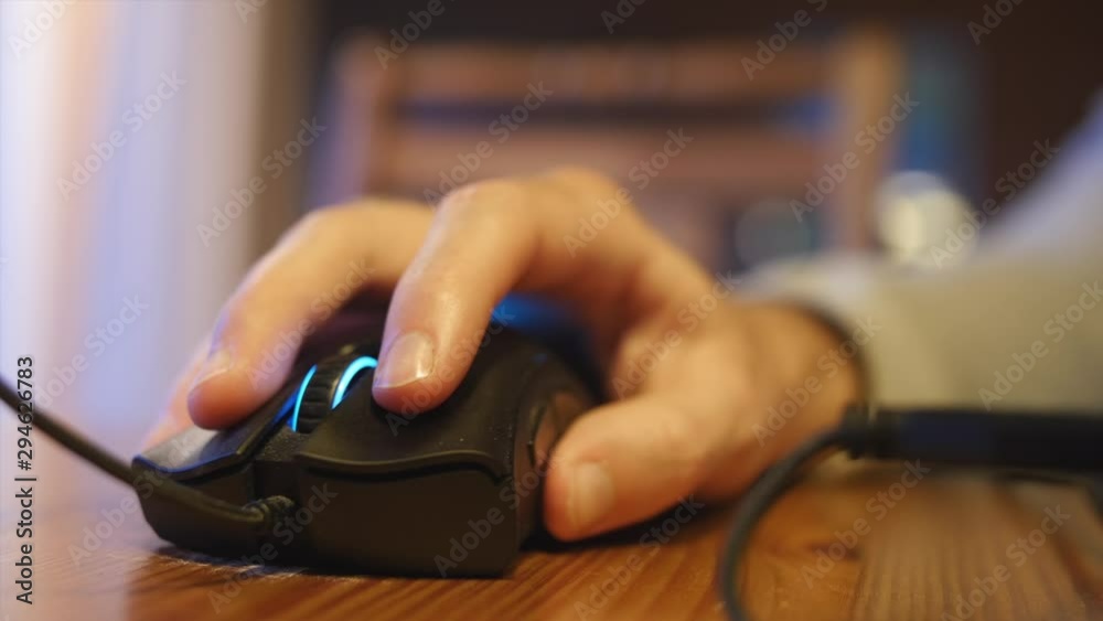 Closeup view of a hand using a computer mouse. Working from home concept or playing video games. Closeup view of a hand using a computer mouse. Working from home concept or playing video games.