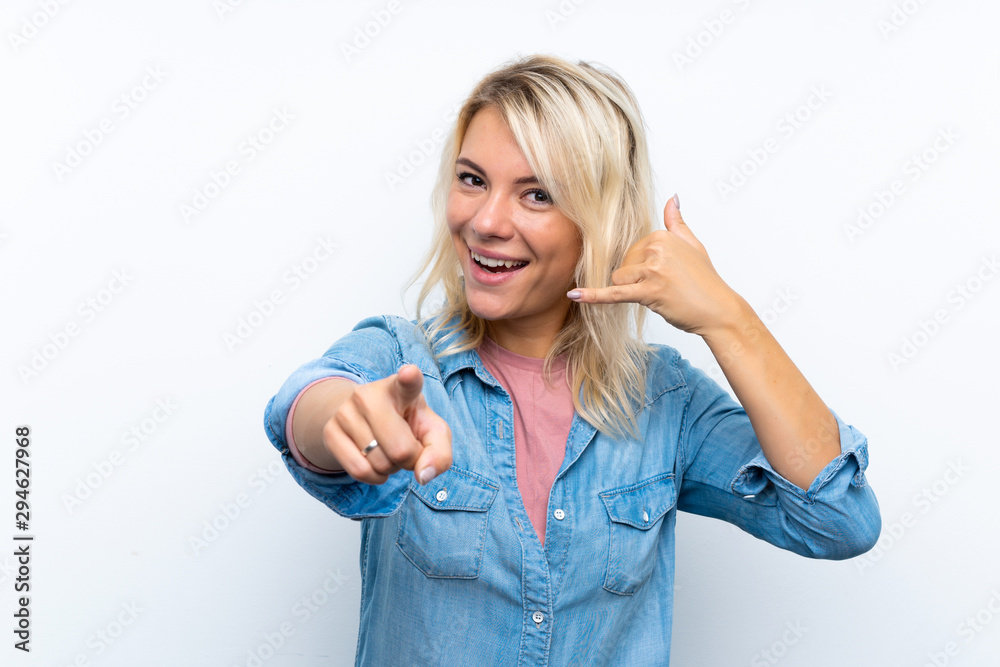 Obraz premium Young blonde woman over isolated white background making phone gesture and pointing front