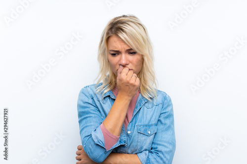 Young blonde woman over isolated white background having doubts