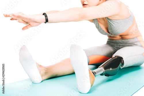 cropped view of disabled sportswoman stretching on fitness mat isolated on white