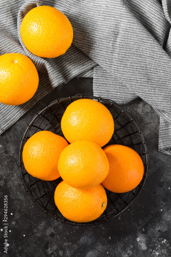 Black metal basket with oranges on a black table