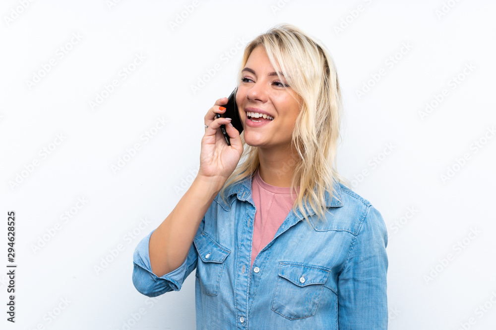 Young blonde woman over isolated white background keeping a conversation with the mobile phone Young blonde woman over isolated white background keeping a conversation with the mobile phone