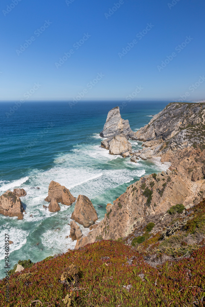 Scenic view of the Atlantic Ocean and rugged coastline with huge boulders near Cabo da Roca, the westernmost point of mainland Europe, in Portugal.