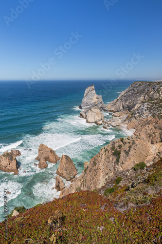 Scenic view of the Atlantic Ocean and rugged coastline with huge boulders near Cabo da Roca, the westernmost point of mainland Europe, in Portugal.