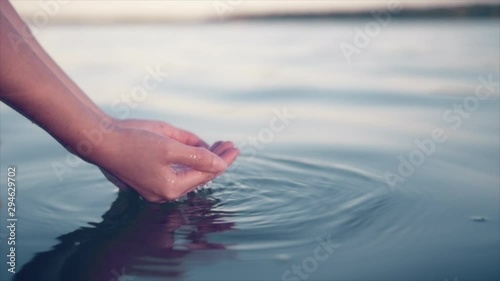 Female hands gather water from a calm lake in northern Sweden, Norrbotten County. Slow motion. photo
