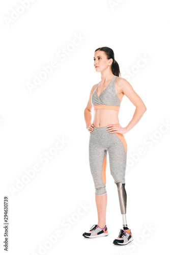 full length view of disabled sportswoman standing with hands on hips isolated on white
