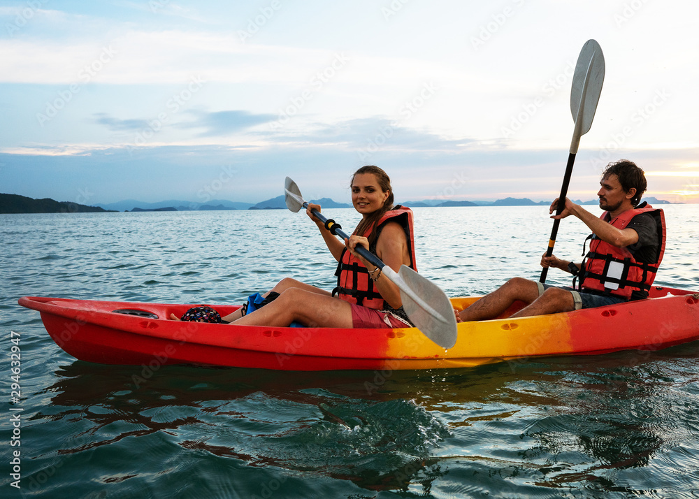 Couple kayaking together. Beautiful young couple kayaking on lake together and smiling at sunset