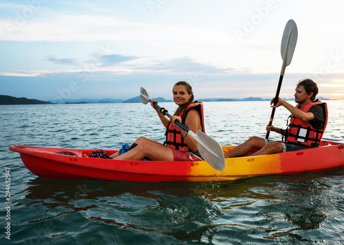 Couple kayaking together. Beautiful young couple kayaking on lake together and smiling at sunset