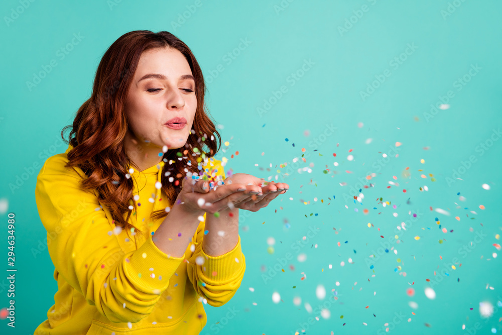 Photo of curly wavy trendy white cheerful charming sweet pretty youngster blowing confetti away from his hands palms enjoying pocess isolated over turquoise vibrant color background - obrazy, fototapety, plakaty 