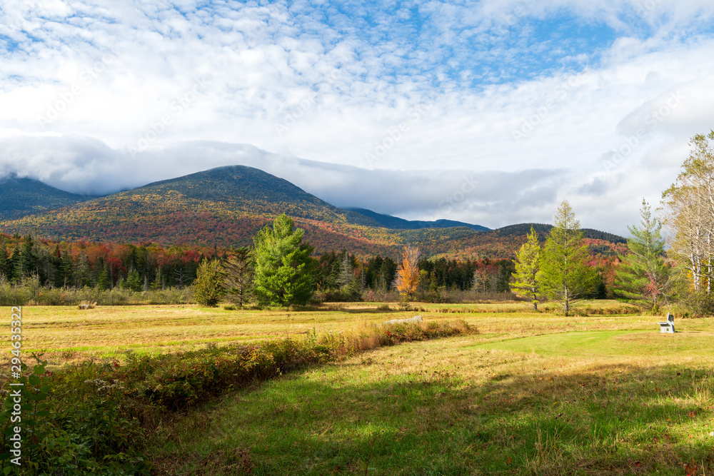 Naklejka premium A photograph of a meadow with mountains and sky with clouds in the background
