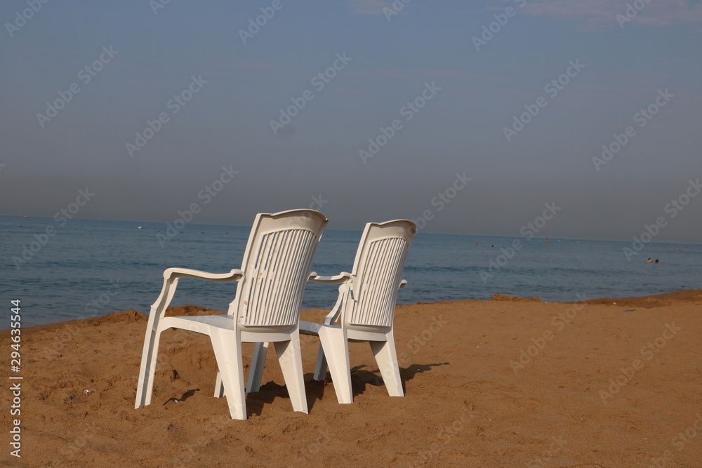 Zwei Stühle am menschenleeren Strand mit Blick auf das Meer
