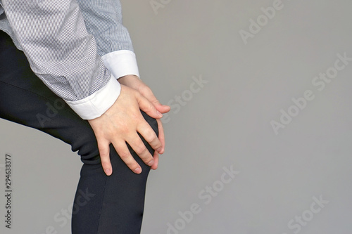 Female hand on the Leg With Painful Knees isolated on gray background. Woman Feeling Joint Pain, Having Health Issues And Touching Leg With Hands. Pain In Knee. Health Care Concept. 