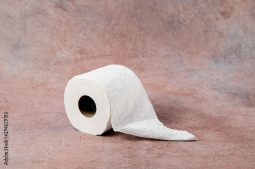 rolls oF soft toilet paper on a dusty pink cloth background