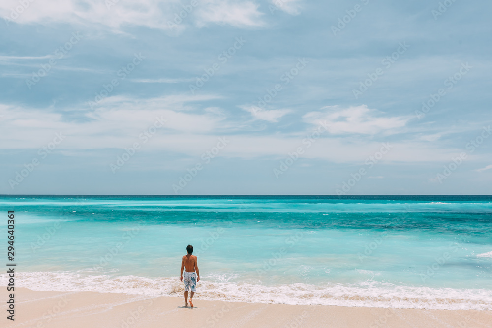 Man walking in blue lagoon with paradise view Man walking in blue lagoon with paradise view