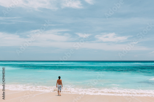 Man walking in blue lagoon with paradise view
