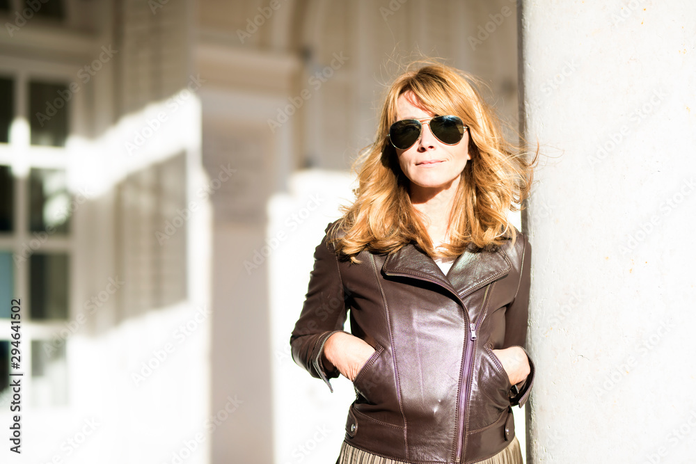 Confident woman enjoy sunshine while relaxing at the wall outdoor Confident woman enjoy sunshine while relaxing at the wall outdoor