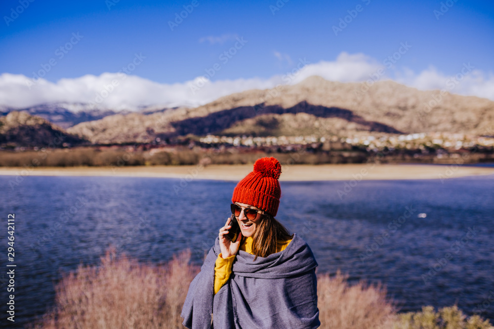 young caucasian woman on the mountain in sunny day talking on mobile phone. Beautiful lake background view. Nature concept young caucasian woman on the mountain in sunny day talking on mobile phone. Beautiful lake background view. Nature concept