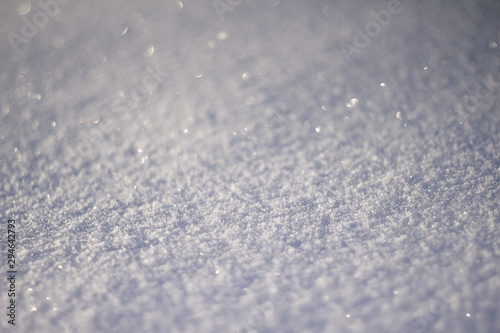 Snowy white background. The texture of the snow. Shiny snow with bokeh and blurred background close-up. White snow-covered field. Macro photo of snow.