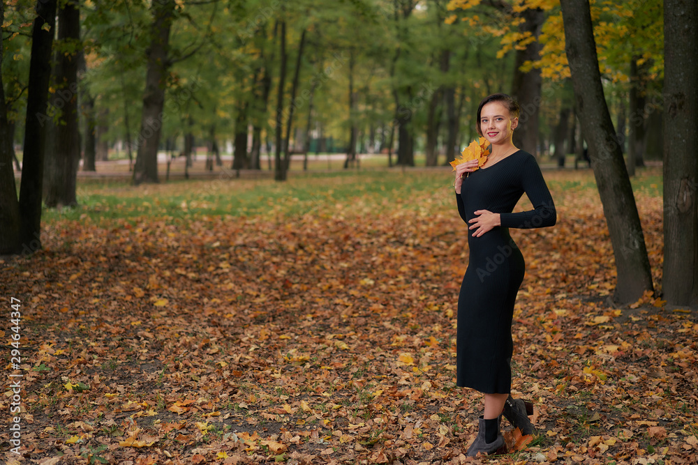 Autumn woman in autumn park with fallen leaves in a black dress. copy space Autumn woman in autumn park with fallen leaves in a black dress. copy space