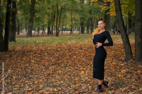Autumn woman in autumn park with fallen leaves in a black dress. copy space