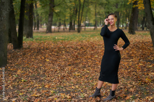 Autumn woman in autumn park in a black dress and glasses