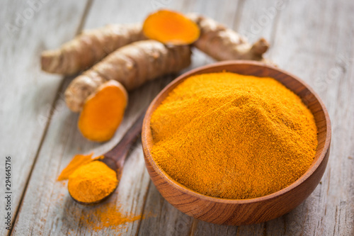 Turmeric powder and roots on wooden background, asian herb for medication