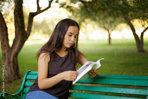 Kazakh beautiful girl reading a book in the summer park