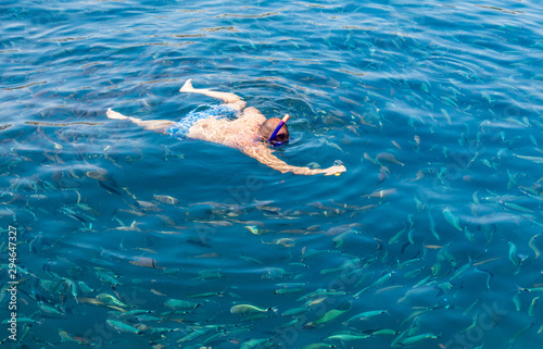 A man swims in the blue water of the sea