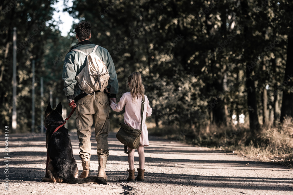 back view of man holding hands with kid near german shepherd dog, post apocalyptic concept back view of man holding hands with kid near german shepherd dog, post apocalyptic concept