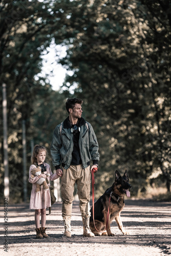 man holding hands with kid near german shepherd dog, post apocalyptic concept