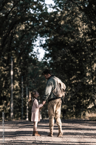 man holding hands with kid while standing on road, post apocalyptic concept © LIGHTFIELD STUDIOS
