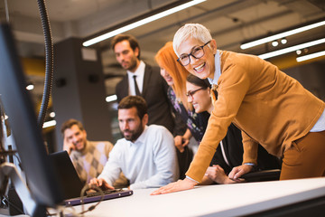 Senior businesswoman working together with young business people in office