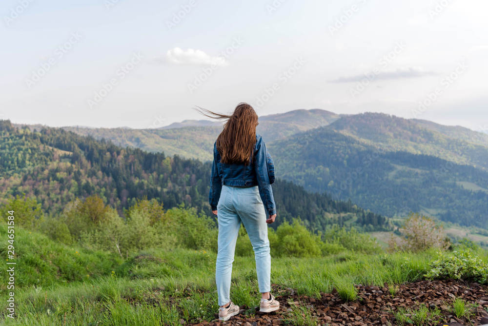 Hipster teenage girl looking at the Carpathians mountains. Girl on top of the mountain watching at sunset.